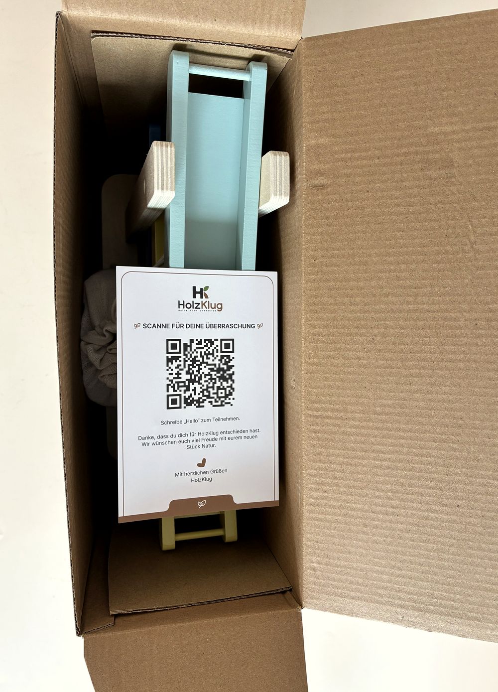 Geöffneter Versandkarton mit der HolzKlug Rampenbahn und der QR-Karte obenauf
